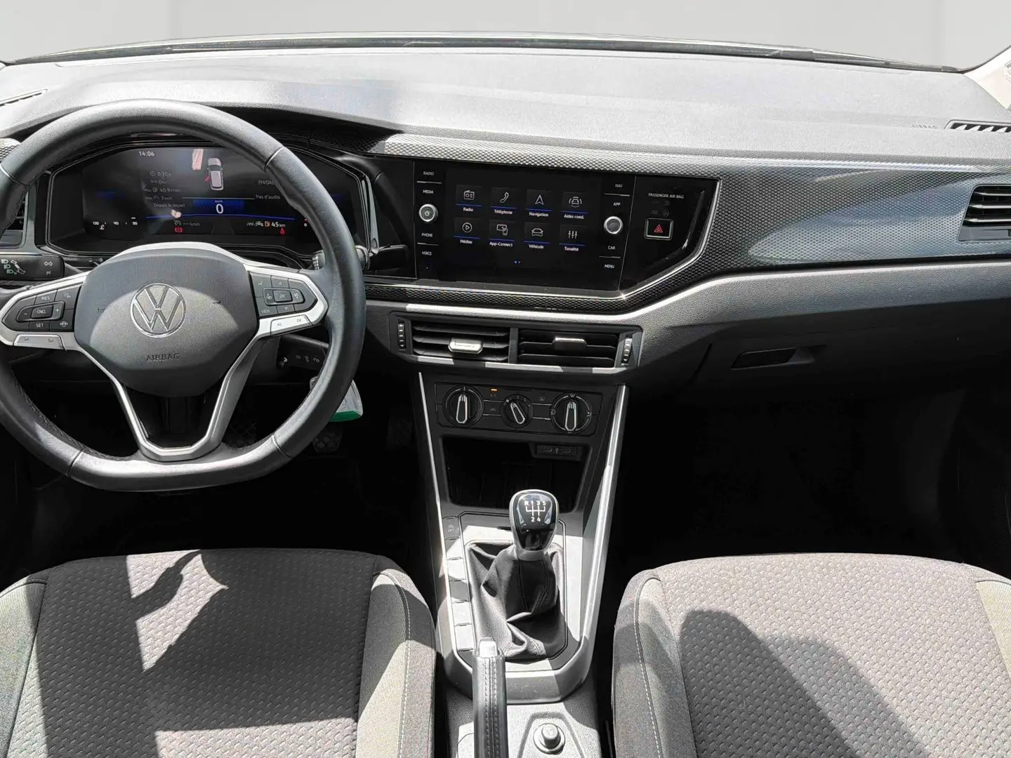 Vue intérieure avant de la Volkswagen Polo 2025 gris, volant multifonctions, écran tactile et levier de vitesse manuel visible.