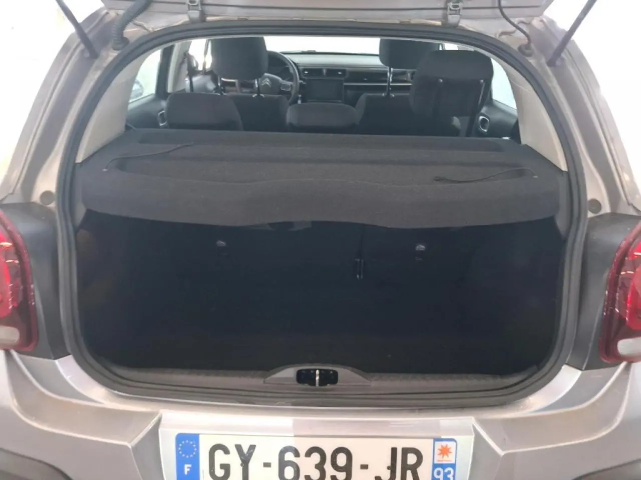Coffre ouvert d'une Citroën C3 gris foncé 2024, vue arrière montrant l'intérieur et la plage arrière.