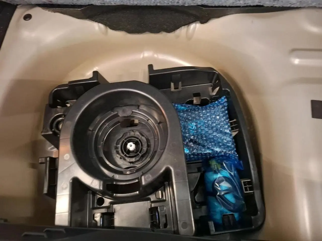 Gros plan sur le rangement sous plancher de coffre d'une Citroën C3 2024 gris foncé, montrant un support et accessoires emballés.