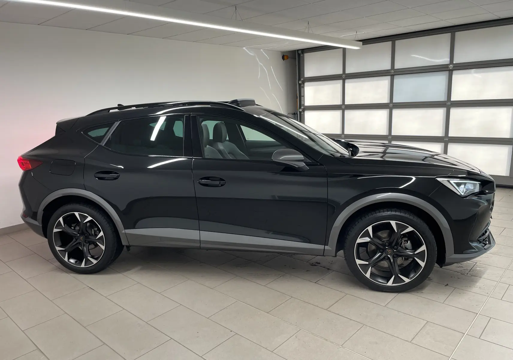 Vue de profil côté gauche d'un CUPRA Formentor 1.5 TSI 150 DSG7 VZ-LINE noir minuit avec jantes noires et grises.