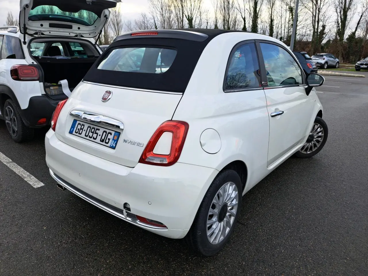 Vue 3/4 arrière droite d'une Fiat 500 Cabriolet blanche avec toit souple noir, immatriculée en France.