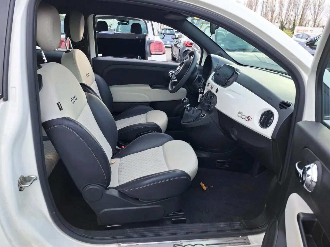 Vue côté gauche de l'intérieur blanc et noir du Fiat 500 Cabriolet 2021 avec tableau de bord épuré et logo 500C.