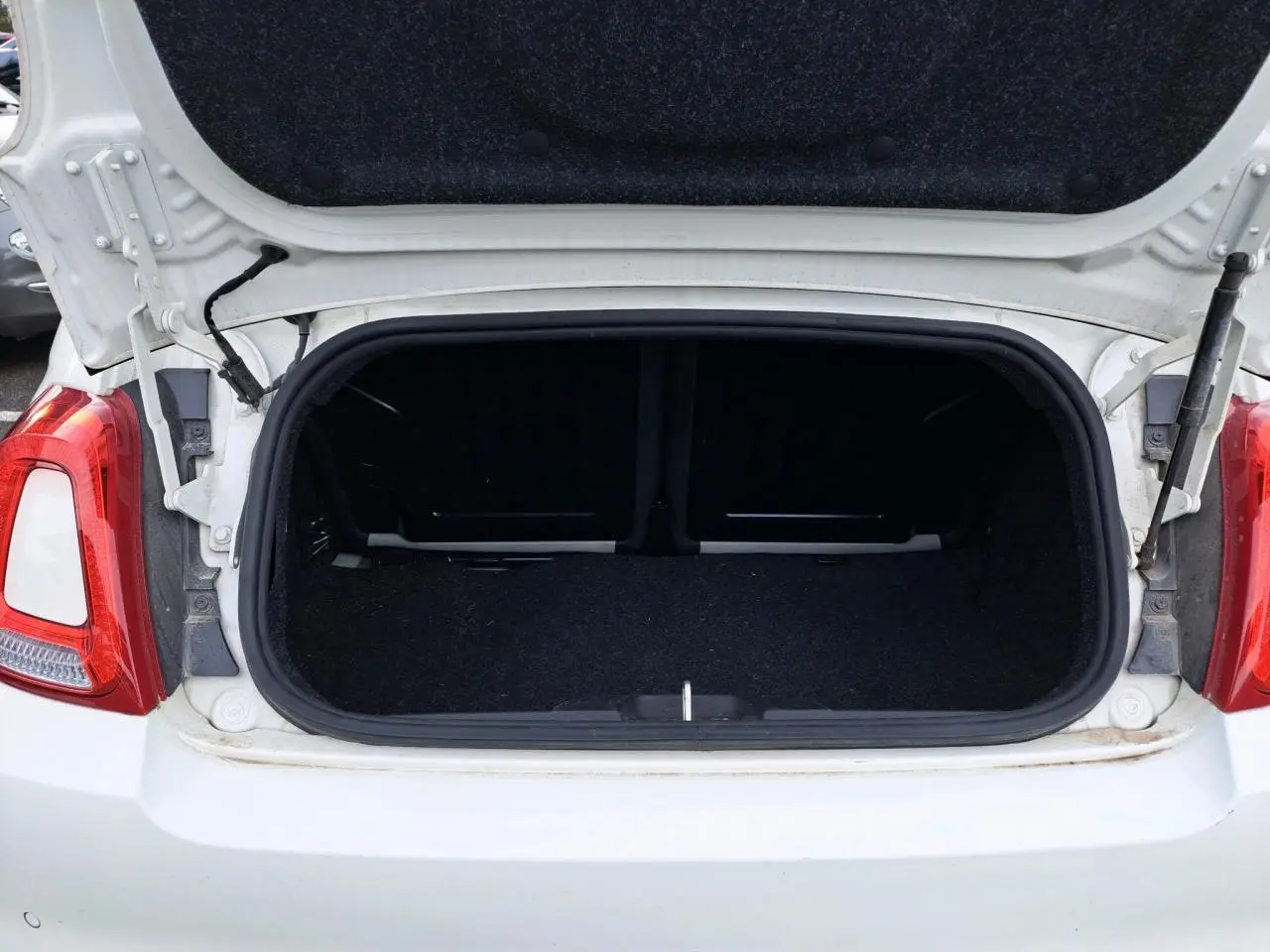 Coffre ouvert vu de l'arrière d'une Fiat 500 Cabriolet blanche de 2021, montrant l'espace de chargement vide.