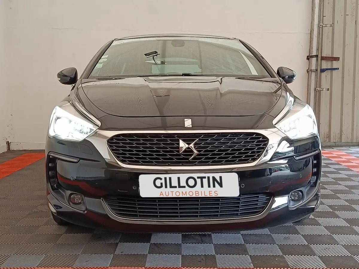 Vue avant d'une DS5 noire avec phares allumés et calandre chromée dans un garage.