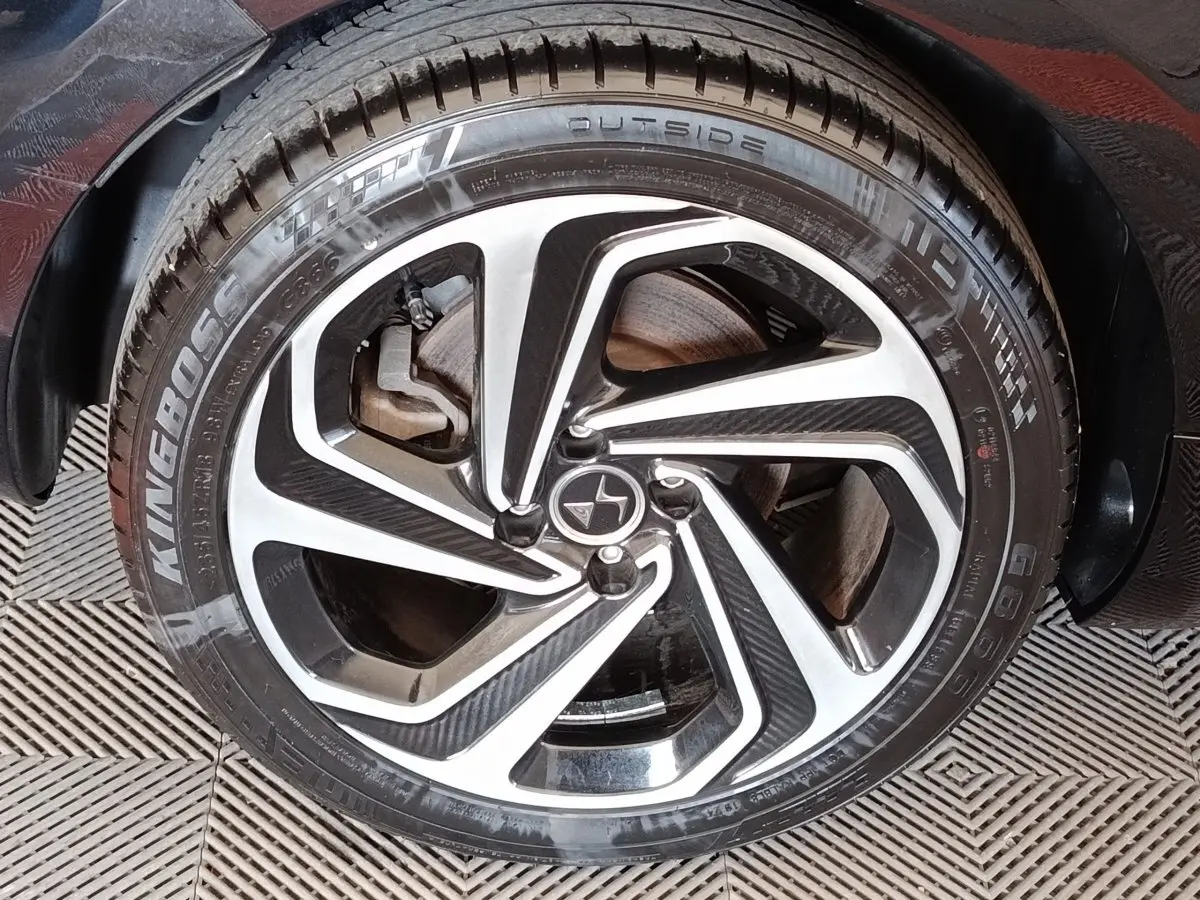 Gros plan sur la roue avant gauche de la DS5 noire, mettant en valeur la jante alliage au design moderne bicolore.
