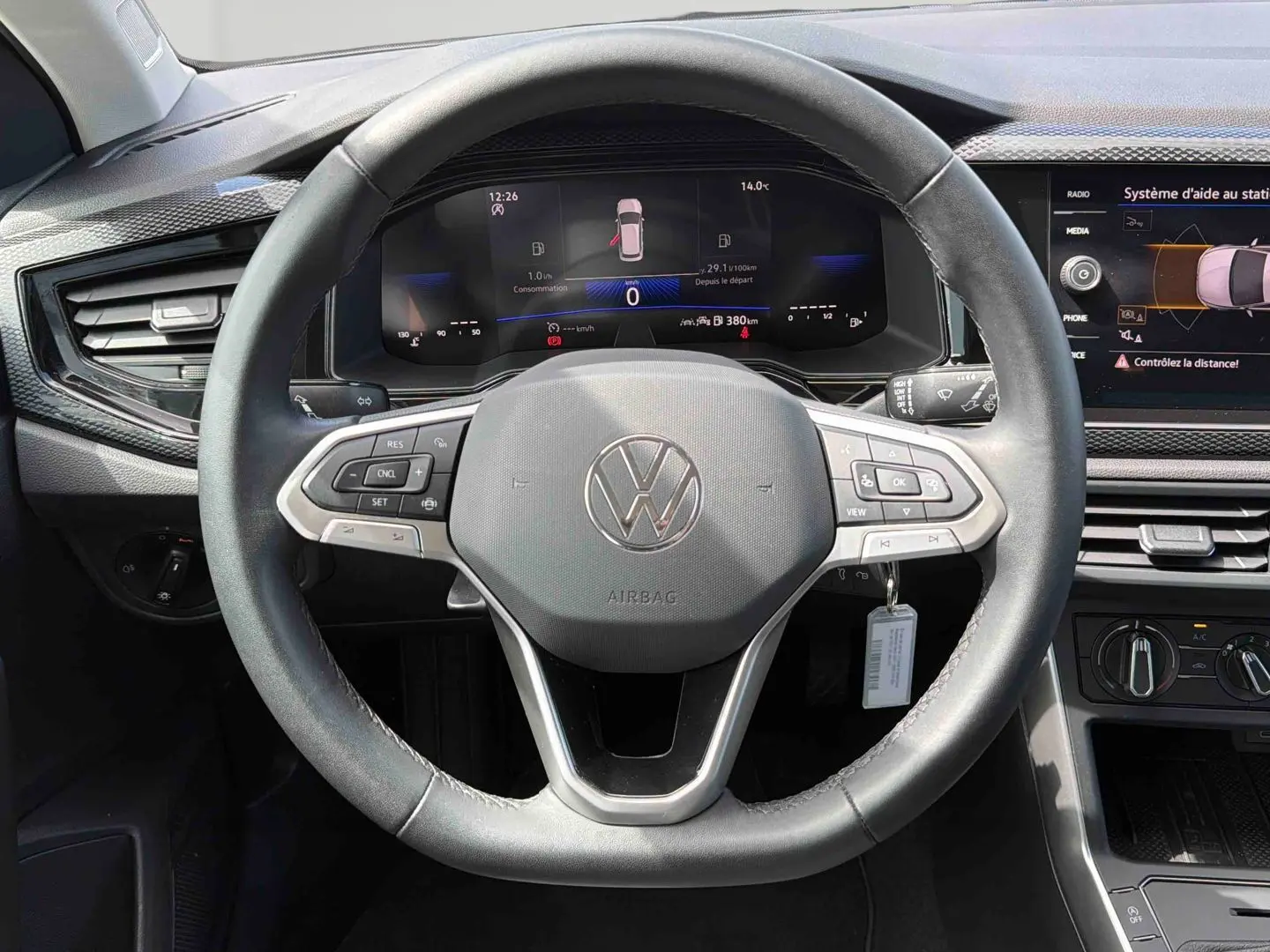 Vue rapprochée du volant multifonctions noir et du tableau de bord digital de la Volkswagen Polo 2025 gris.