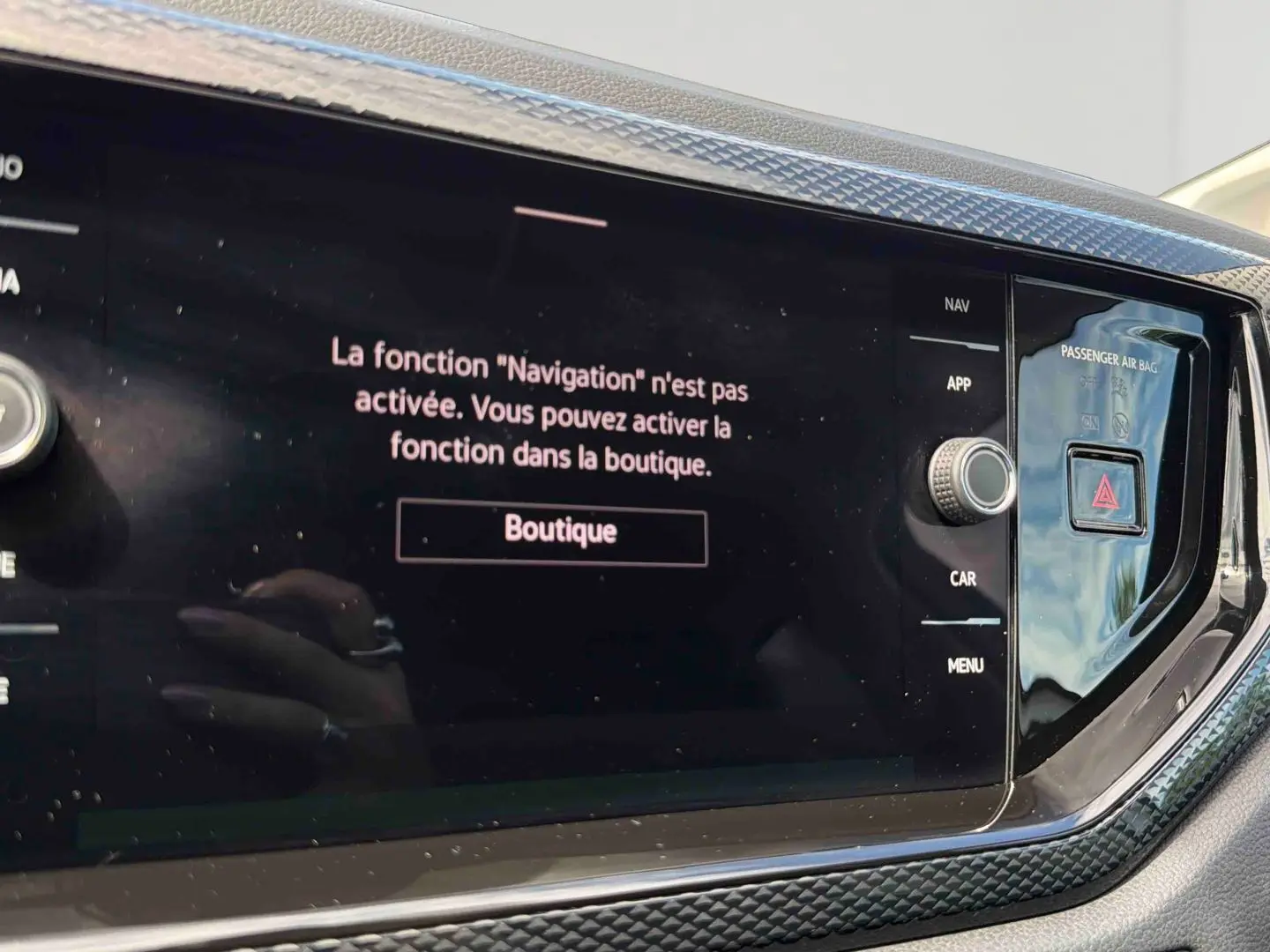 Gros plan sur l'écran tactile central noir de la Volkswagen Polo grise, affichant un message d'activation de la navigation.