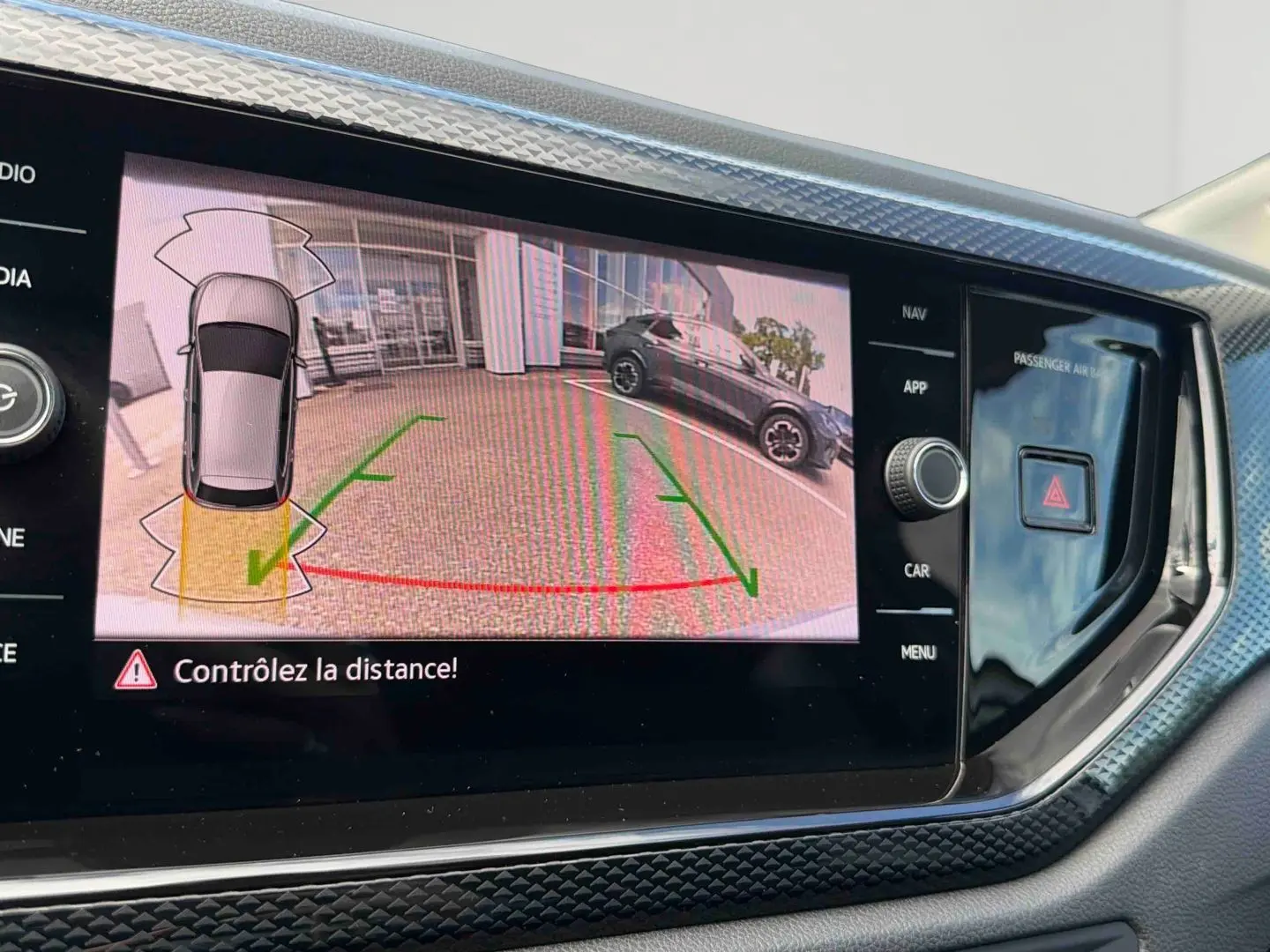 Écran tactile intérieur montrant la caméra de recul avec vue arrière d'une Volkswagen Polo grise stationnée.