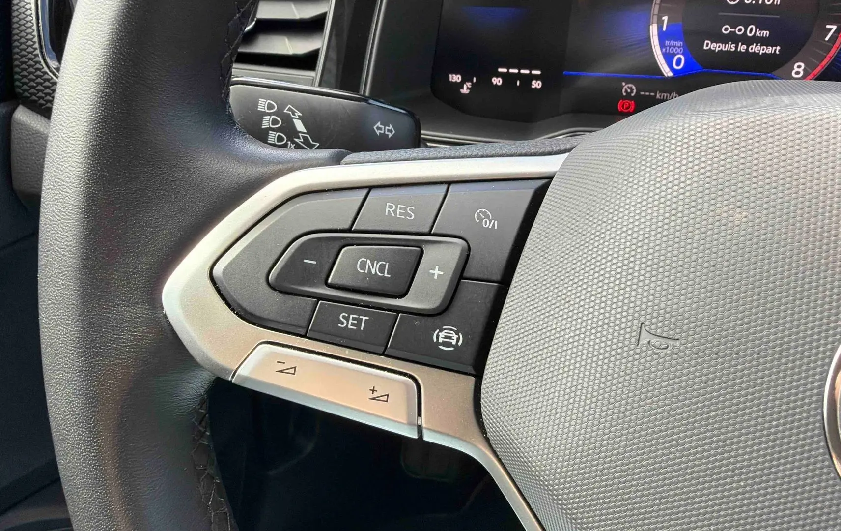 Gros plan sur le volant multifonctions de la Volkswagen Polo 2025, avec commandes de régulateur de vitesse et combiné digital visible.