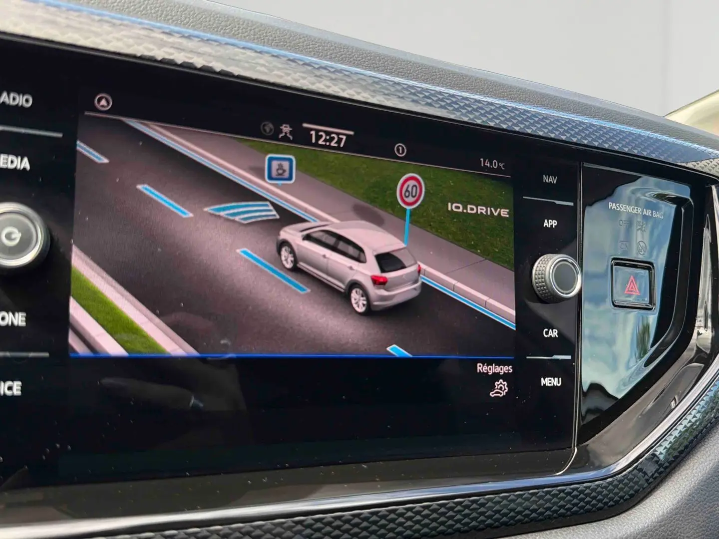 Écran tactile intérieur montrant la Polo grise vue de dessus en simulation de conduite avec signalisation routière.