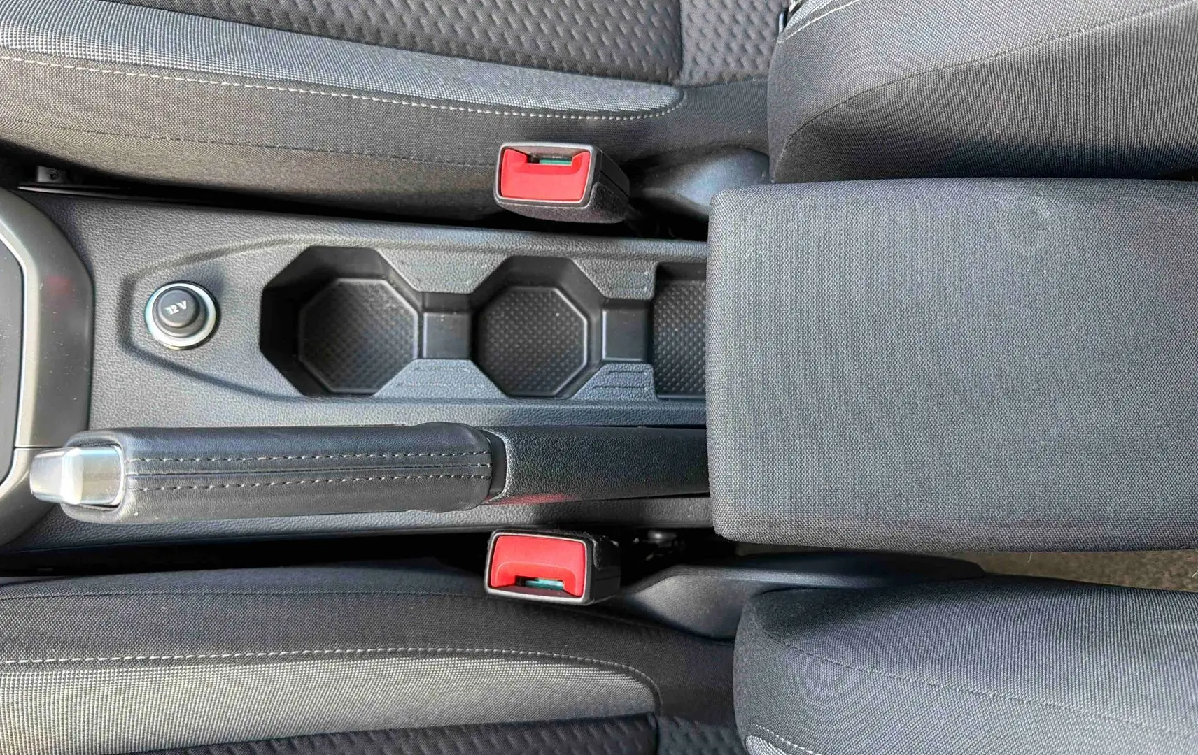 Vue plongeante sur la console centrale noire de la Volkswagen Polo 2025 avec frein à main et accoudoir tissu.