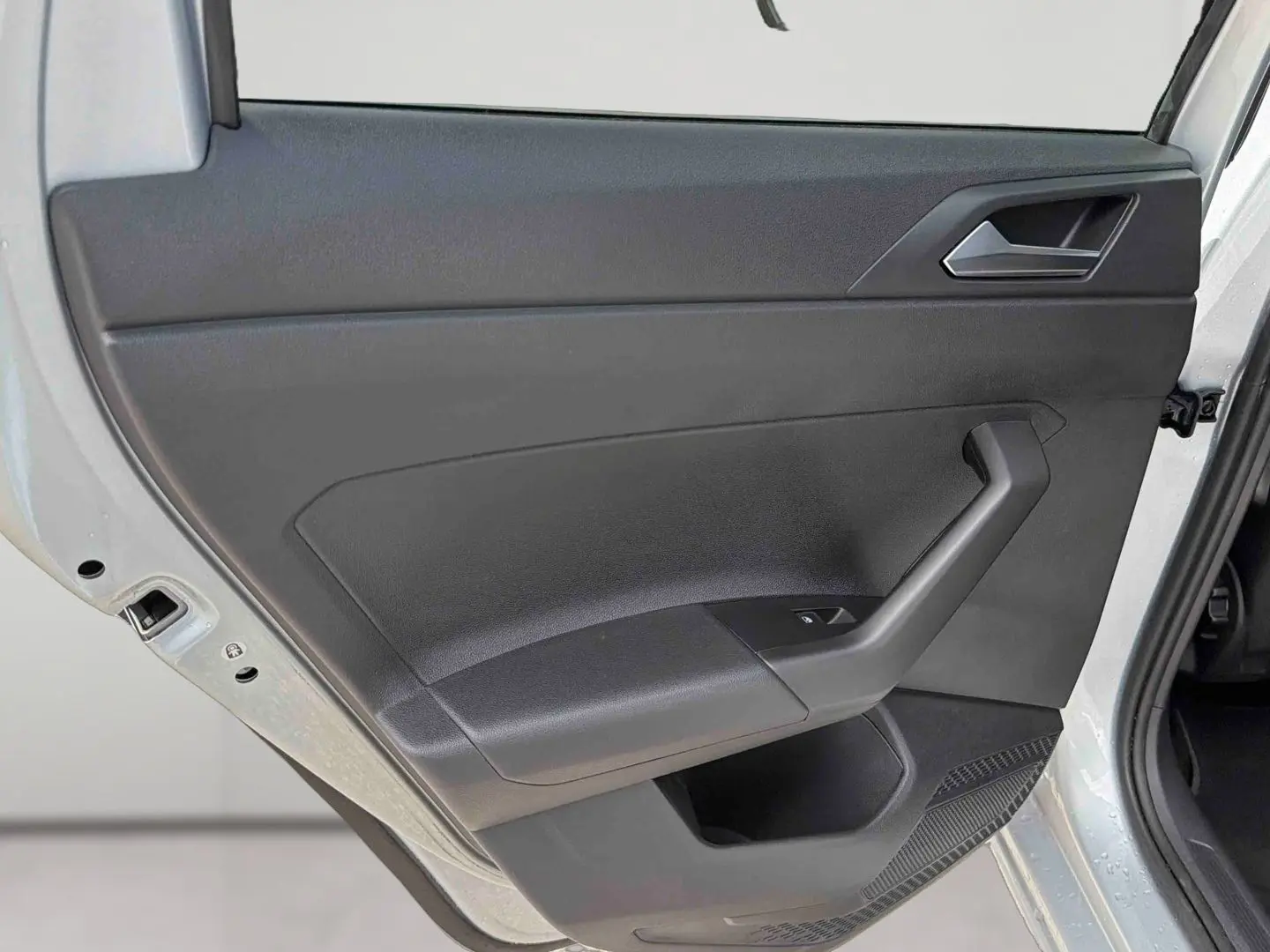 Vue rapprochée de la porte arrière gauche grise d'une Volkswagen Polo 2025 avec poignée et commande de lève-vitre.