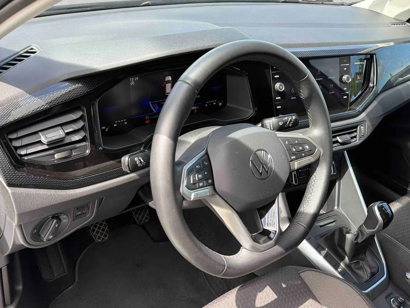 Vue intérieure centrée sur le volant et tableau de bord digital de la Volkswagen Polo grise avec boîte manuelle.