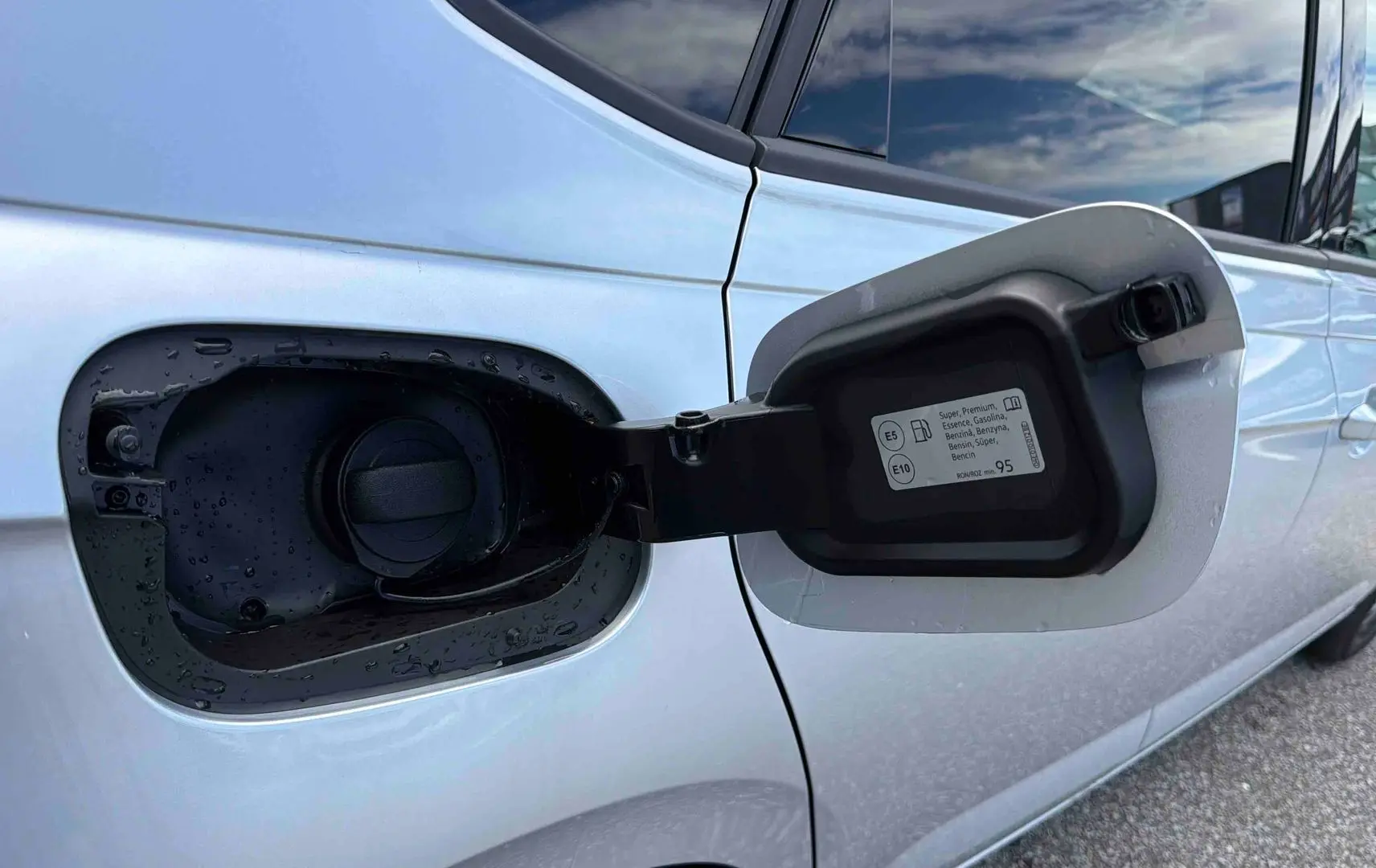 Vue rapprochée de la trappe à carburant ouverte côté gauche d’une Volkswagen Polo grise 2025.
