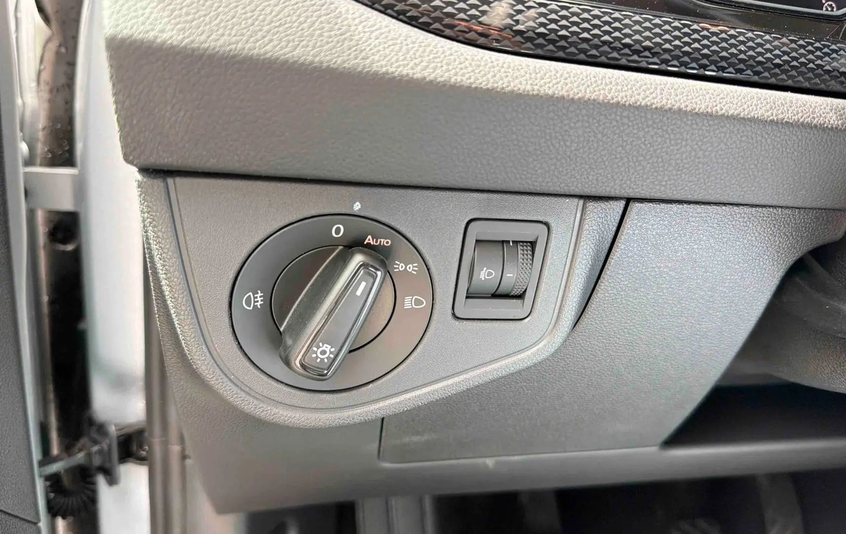 Détail du bouton de commande des phares sur le tableau de bord gris d'une Volkswagen Polo 2025.