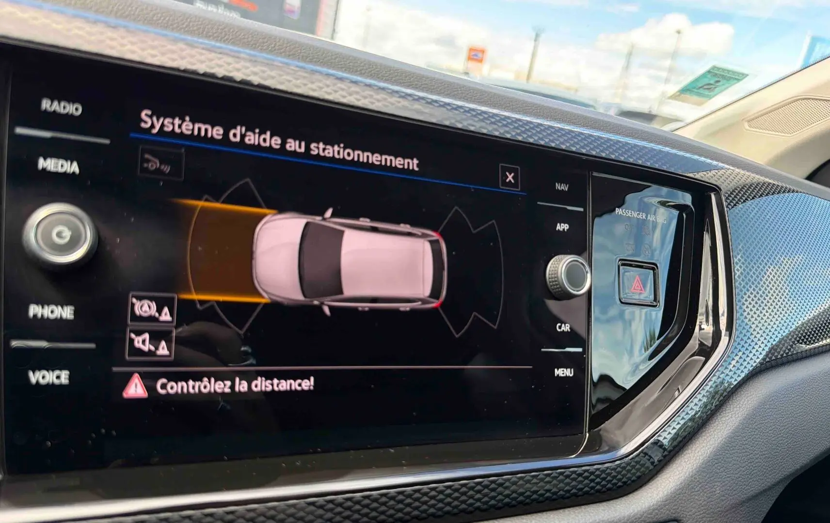 Écran tactile intérieur montrant l'aide au stationnement de la Volkswagen Polo grise, vue de face du tableau de bord.