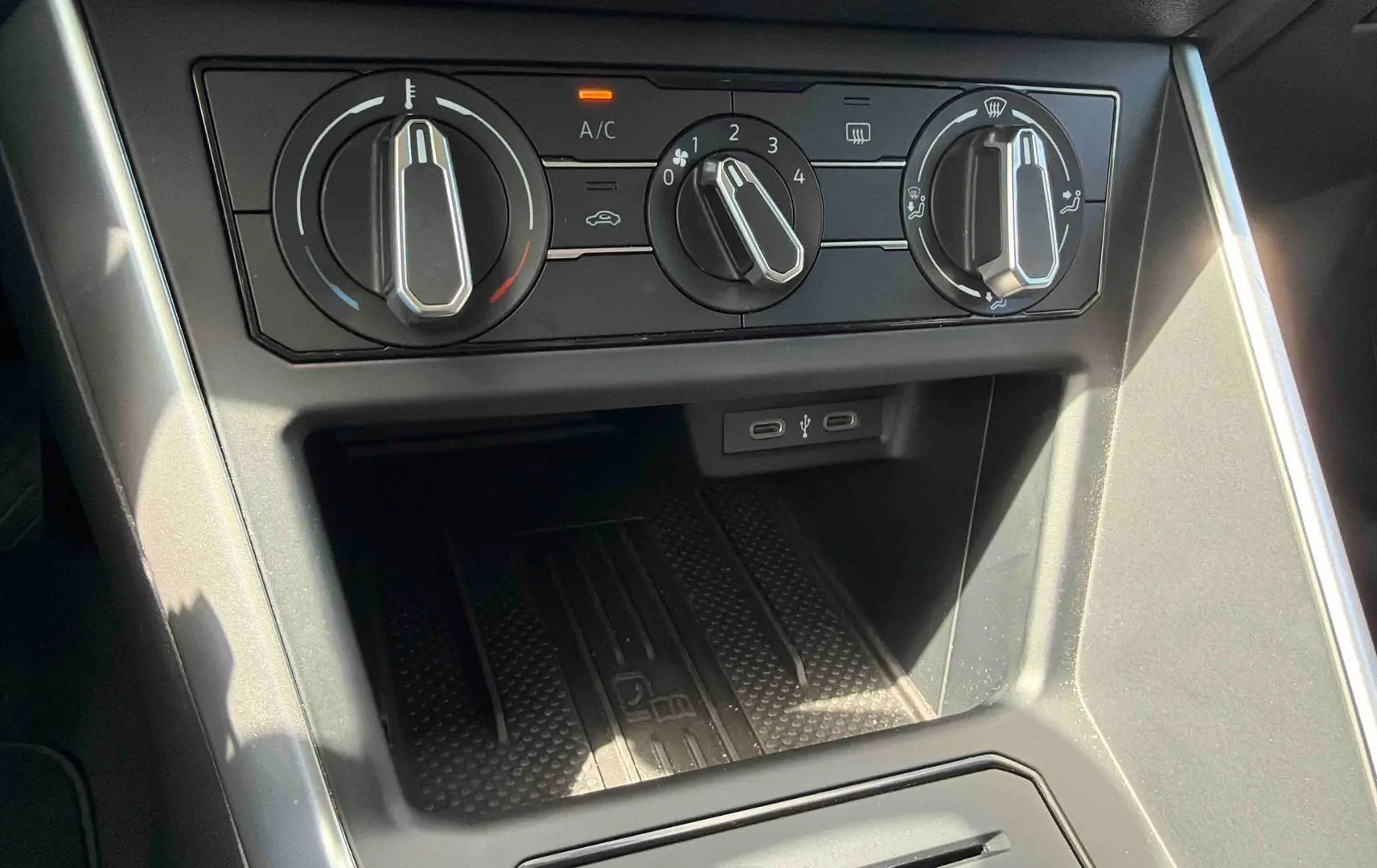 Gros plan sur la console centrale de la Volkswagen Polo grise, montrant les commandes de climatisation manuelle et ports USB-C.