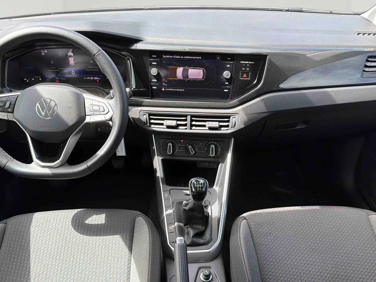 Vue intérieure avant de la Volkswagen Polo grise 2025, avec tableau de bord digital et levier de vitesses manuel.