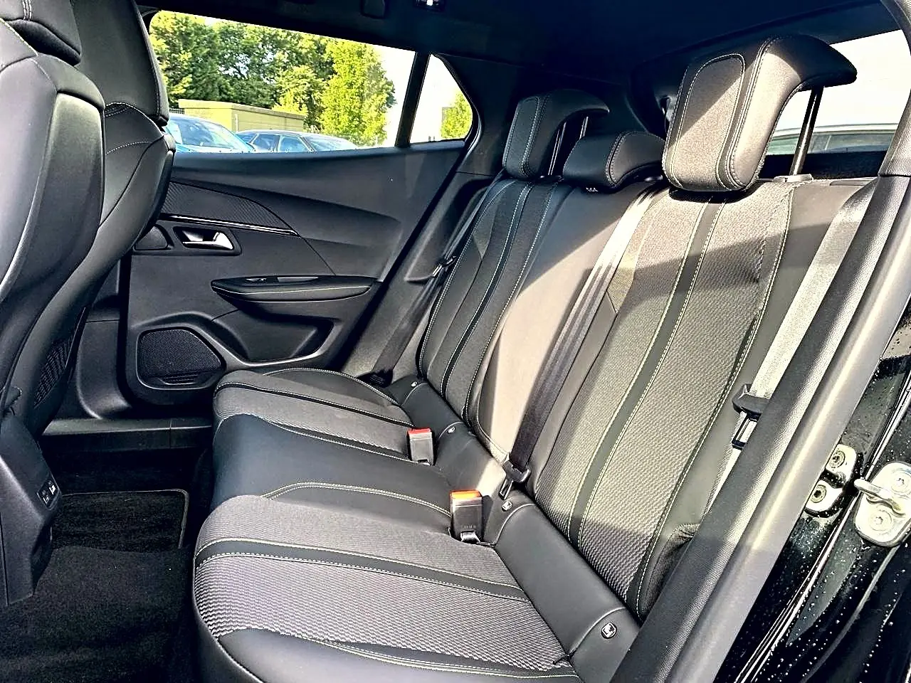 Vue latérale intérieure du siège arrière noir de la Peugeot 2008 1.2 hybrid 145 GT e-DCS6 avec surpiqûres contrastantes.