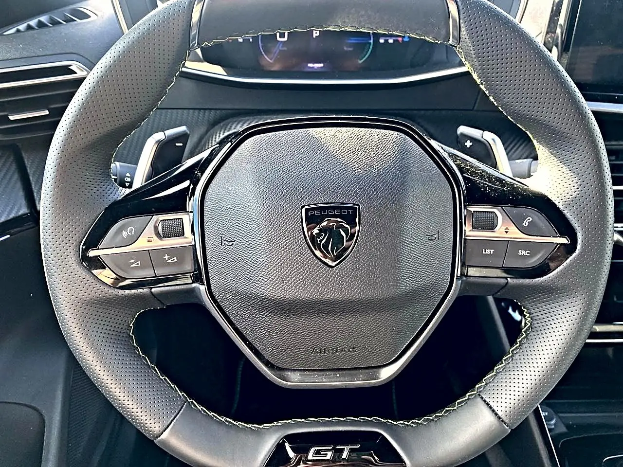 Vue rapprochée du volant cuir noir perforé avec logo Peugeot et badge GT au centre, intérieur du Peugeot 2008 2025.