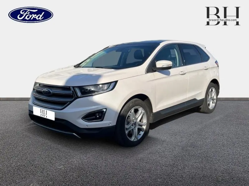 Vue 3/4 avant droit d'un Ford Edge blanc Platinum avec calandre chromée et jantes alliage sur fond clair.