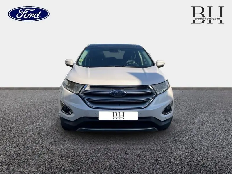 Vue avant d'un Ford Edge blanc Platinum 2016 avec calandre chromée et phares LED dynamiques allumés.