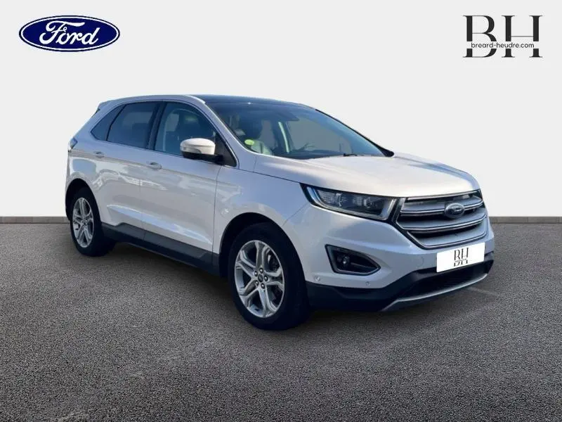 Ford Edge blanc Platinum en vue 3/4 avant droit, mettant en valeur sa calandre chromée et ses jantes alu.