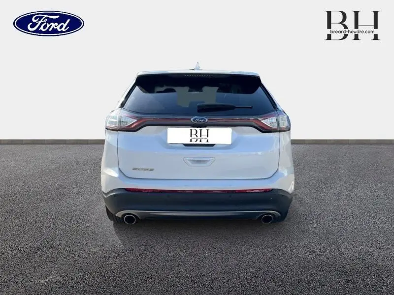 Vue arrière d'un Ford Edge blanc Platinum de 2016 avec double sortie d'échappement et feux arrière LED reliés.