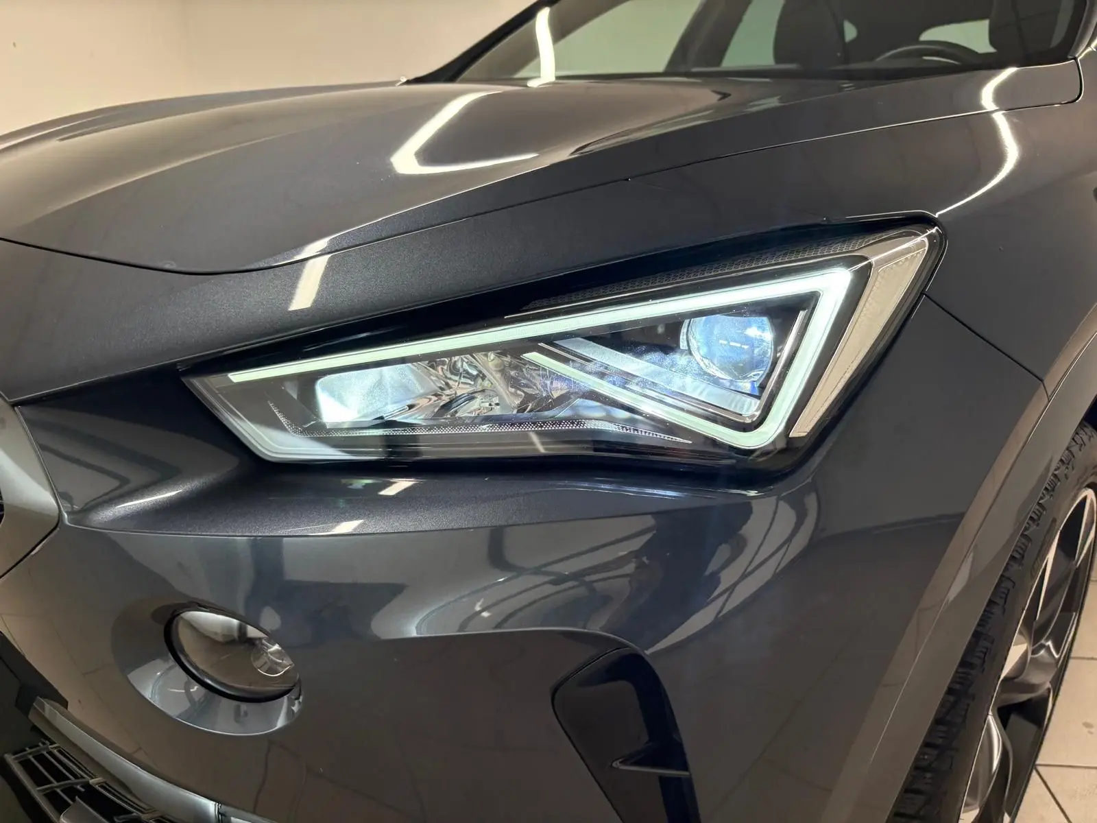 Gros plan sur le phare avant droit du CUPRA Formentor gris magnétique, soulignant son design anguleux et moderne.