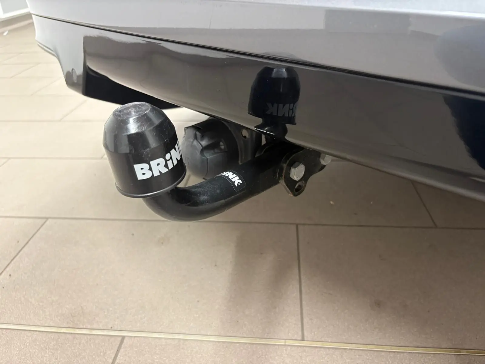 Gros plan sur l'attelage de remorque noir avec protection BRiNK sous le pare-chocs gris magnétique d'une CUPRA Formentor 2023.