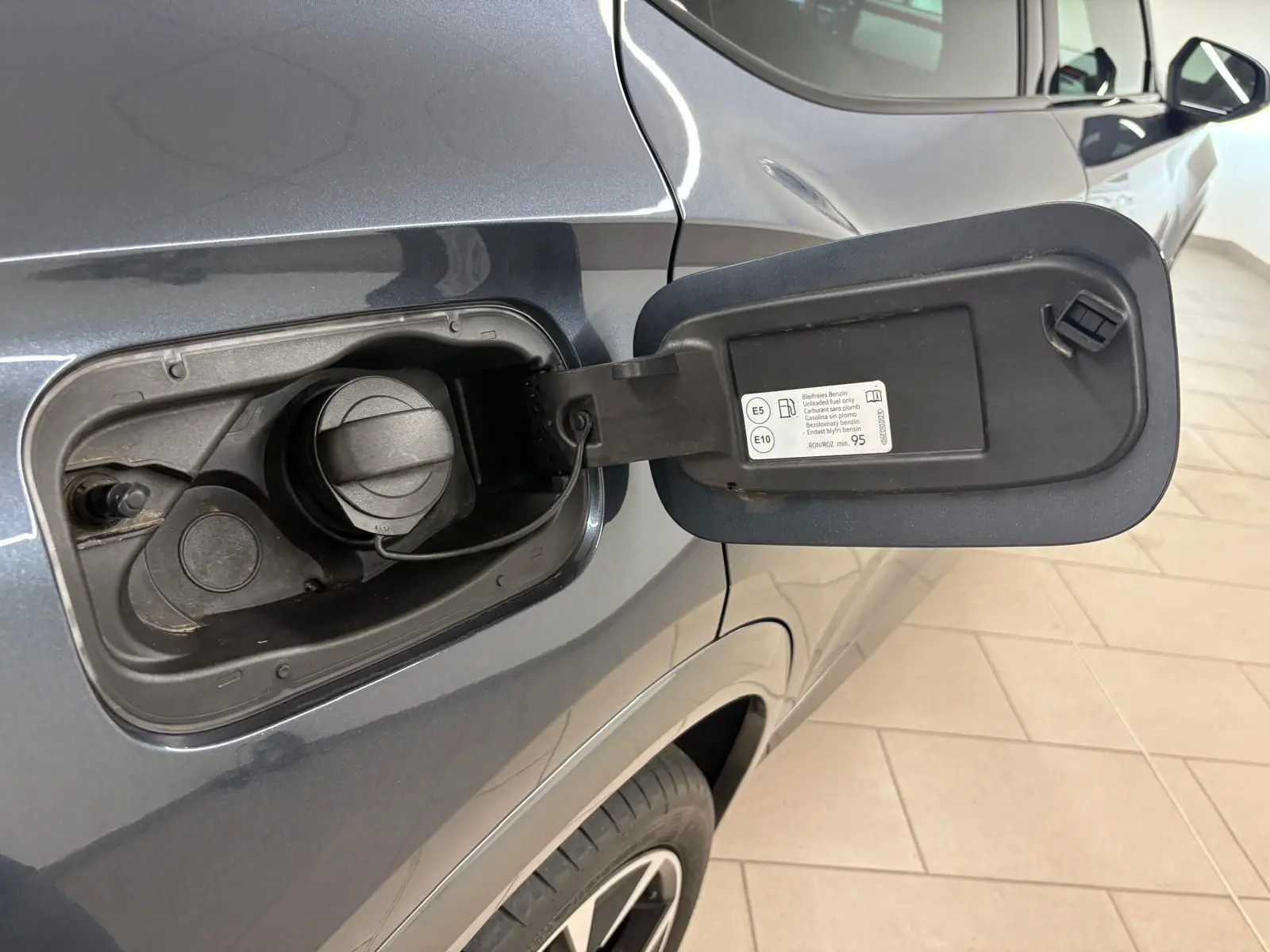 Bouchon de réservoir essence ouvert côté gauche sur CUPRA Formentor gris magnétique 2023, vue rapprochée du volet de remplissage.