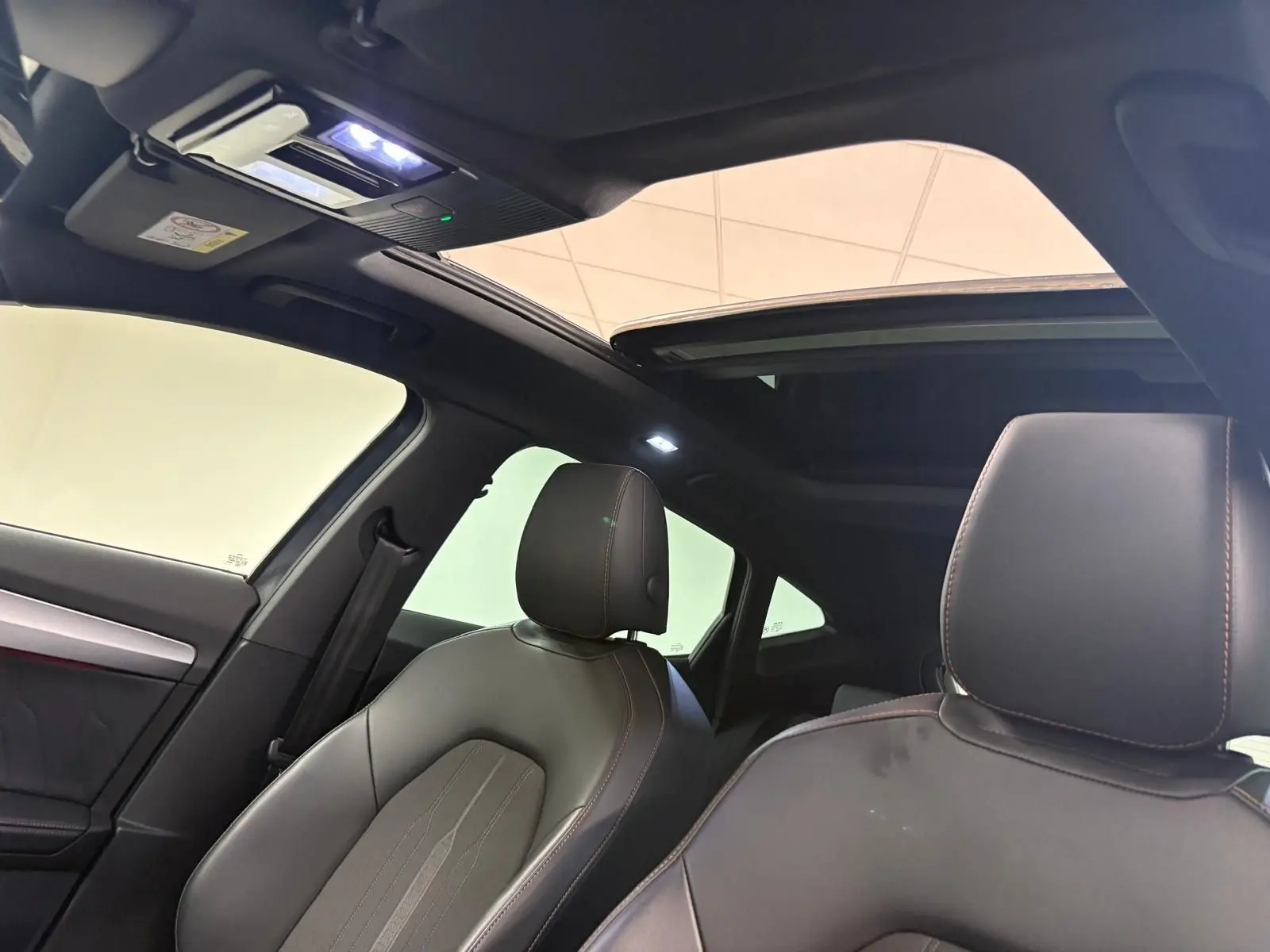 Intérieur du CUPRA Formentor 2023 avec toit ouvrant panoramique et sièges en cuir noir vus côté gauche.