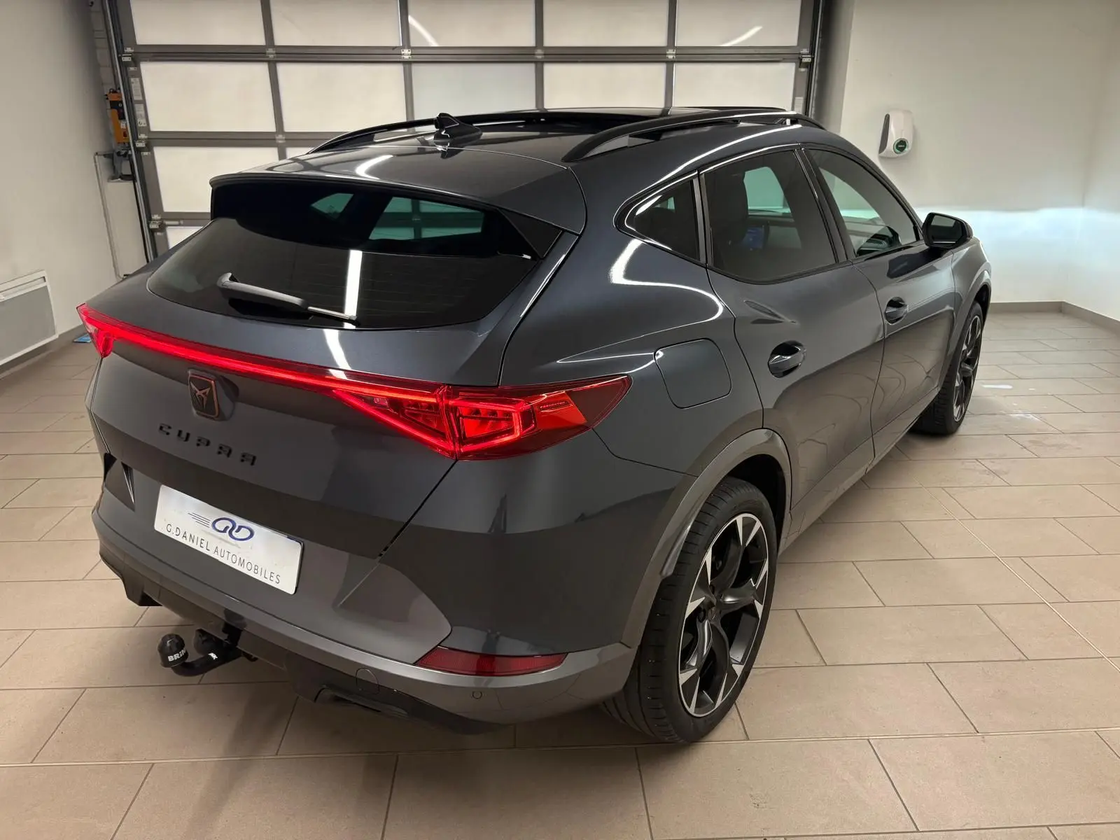 Vue 3/4 arrière droite du CUPRA Formentor gris magnétique 2023 avec feux arrière LED et attelage visible.