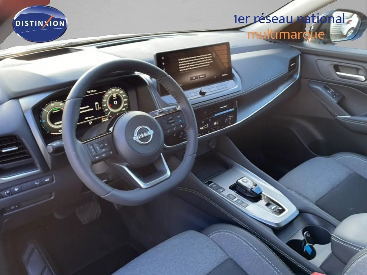 Vue intérieure côté conducteur du Nissan Qashqai 2025 gris argile, avec tableau de bord numérique et écran tactile central.