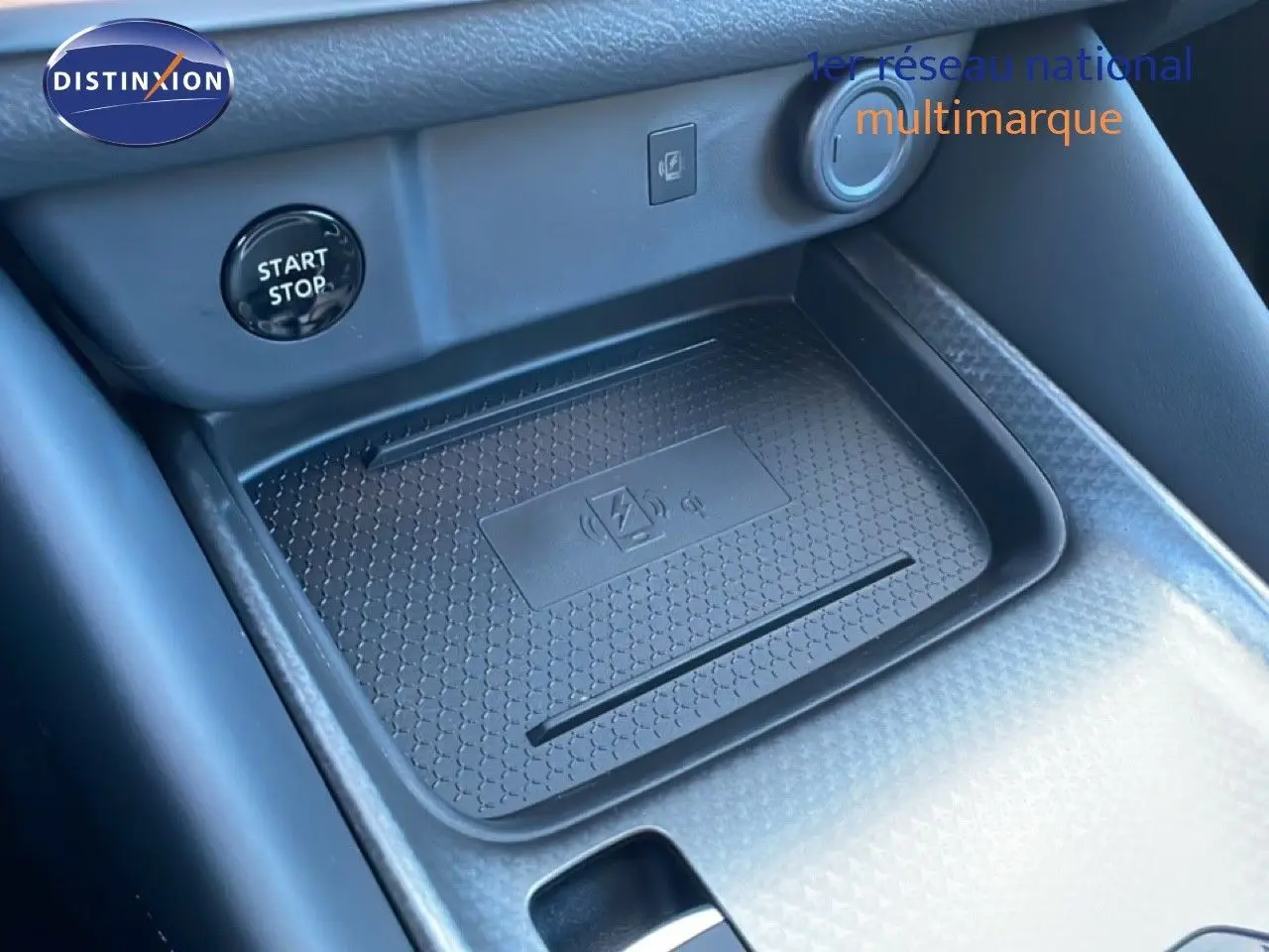 Détail de la console centrale avec surface de charge sans fil et bouton start/stop dans un Nissan Qashqai gris argile.