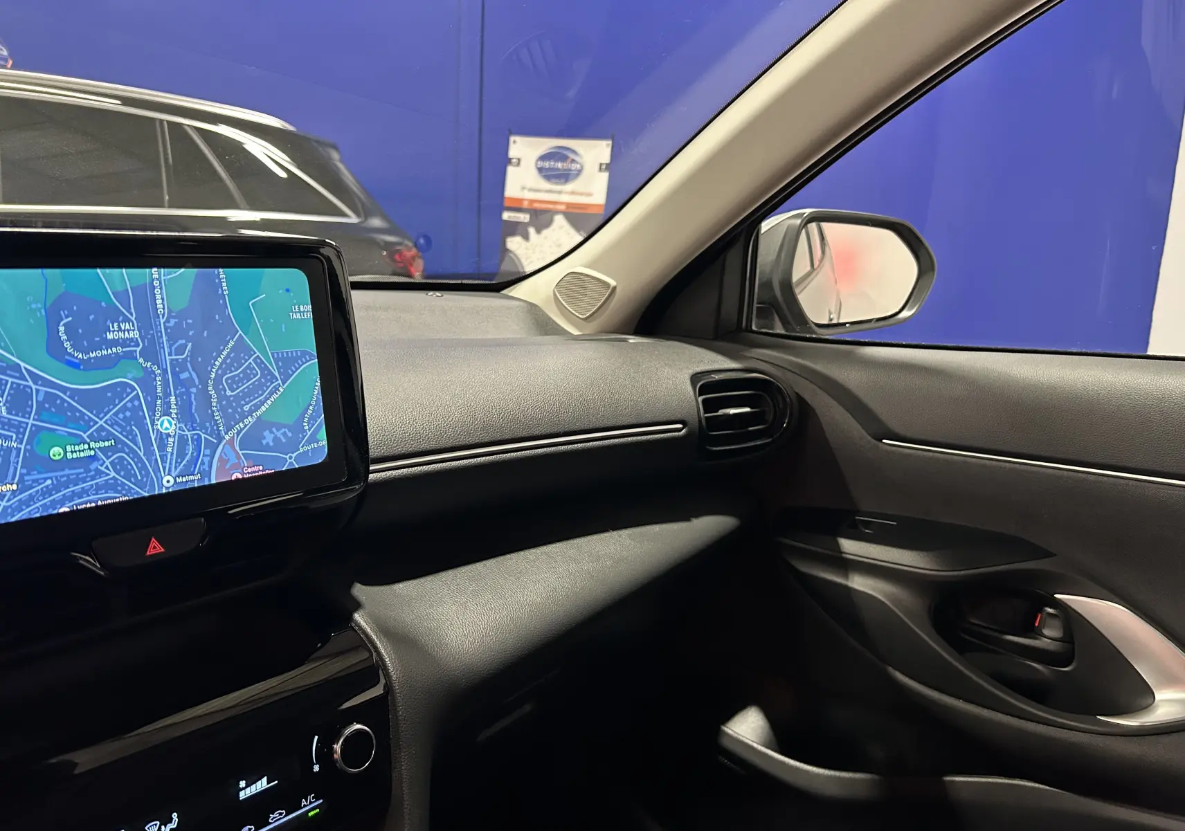Vue intérieure côté passager de la Toyota Yaris Cross 2025, avec écran tactile affichant la navigation et tableau de bord noir.
