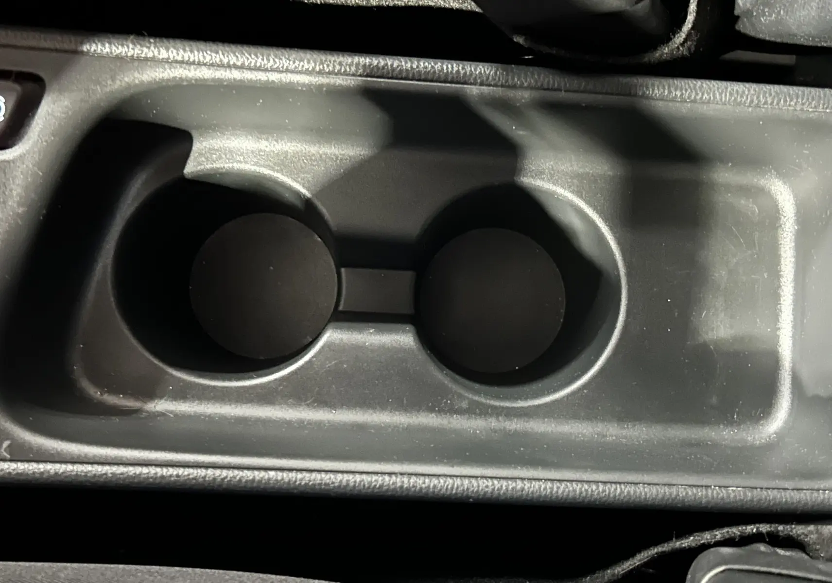 Gros plan sur le porte-gobelets central noir de l'intérieur d'une Toyota Yaris Cross 116h Active MC24 gris minéral.