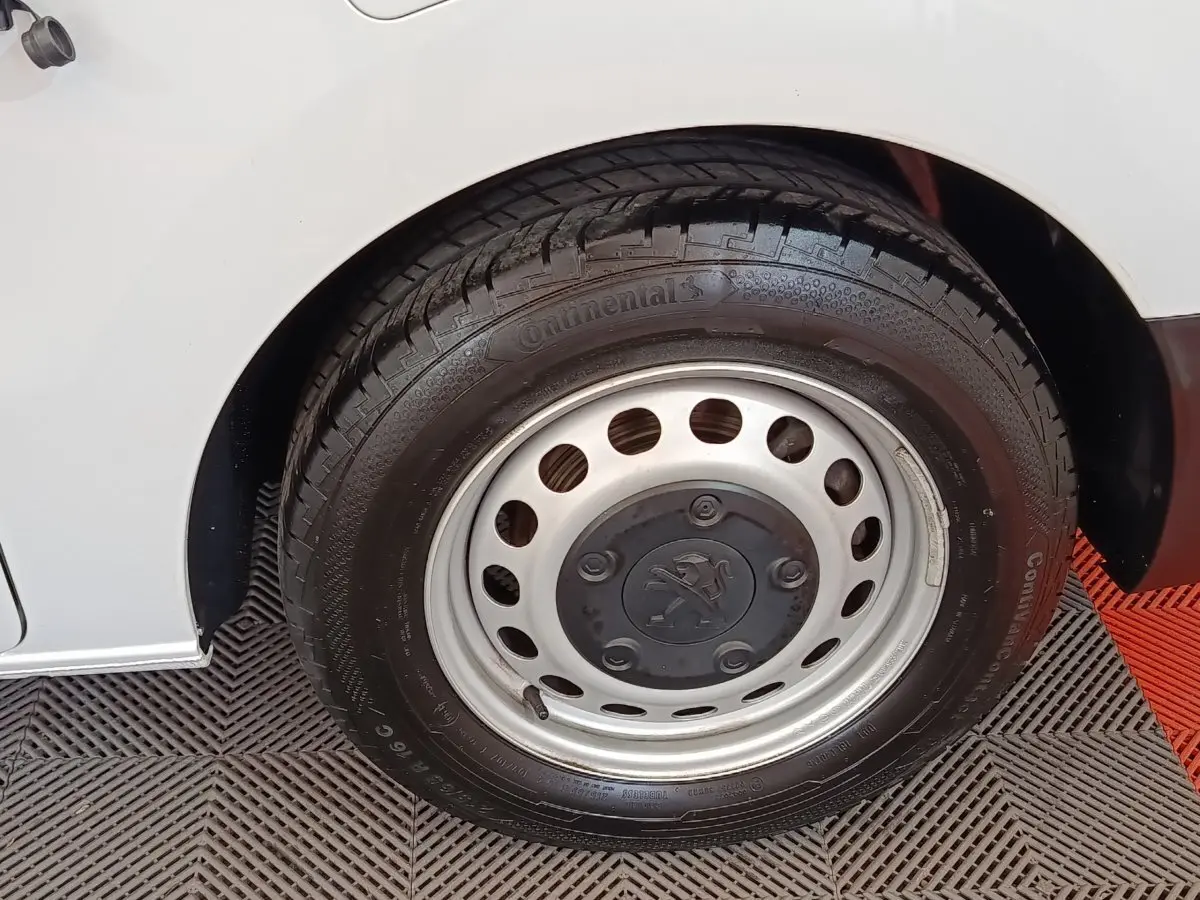 Gros plan sur la roue arrière droite d’un Peugeot Expert Fourgon blanc, jante acier avec logo Peugeot central.