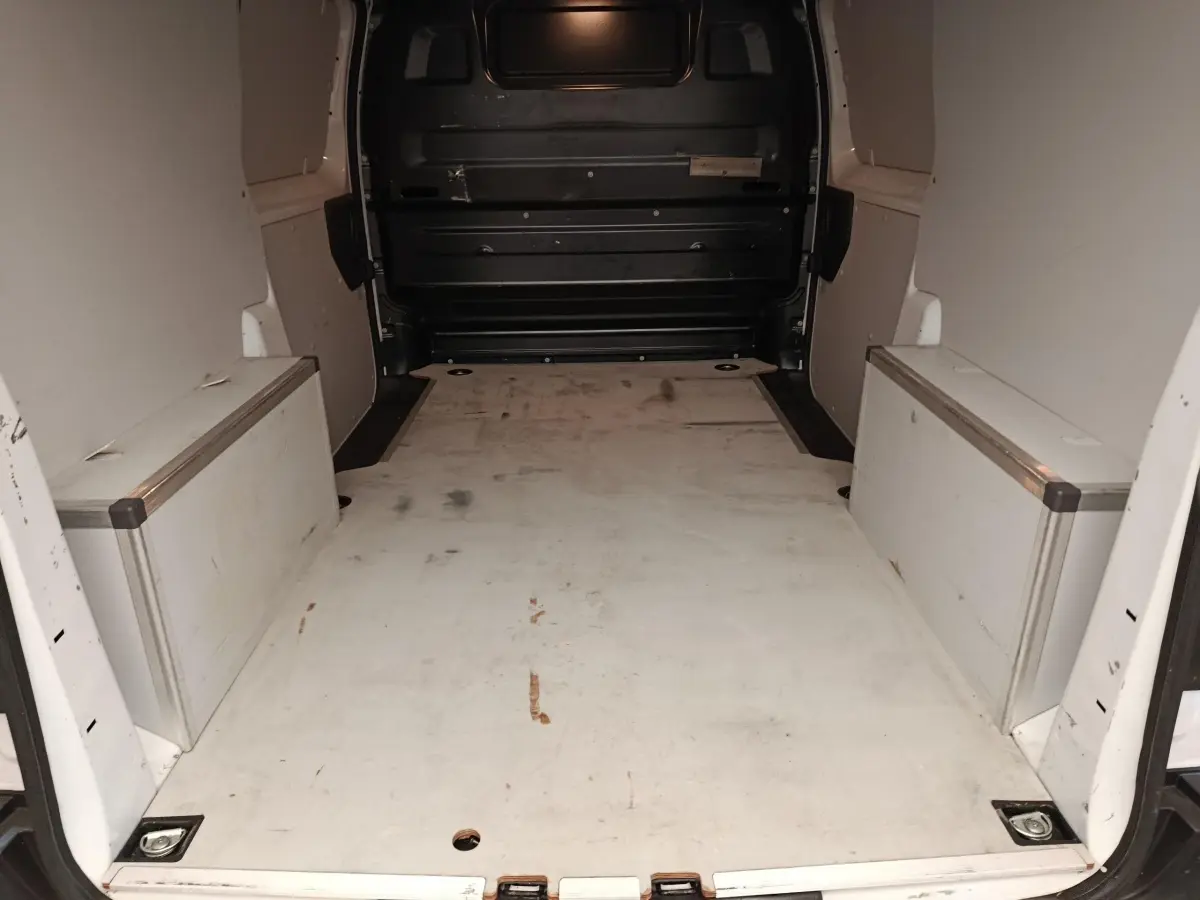 Vue intérieure arrière du fourgon blanc Peugeot Expert avec espace de chargement vide et cloison pleine noire.