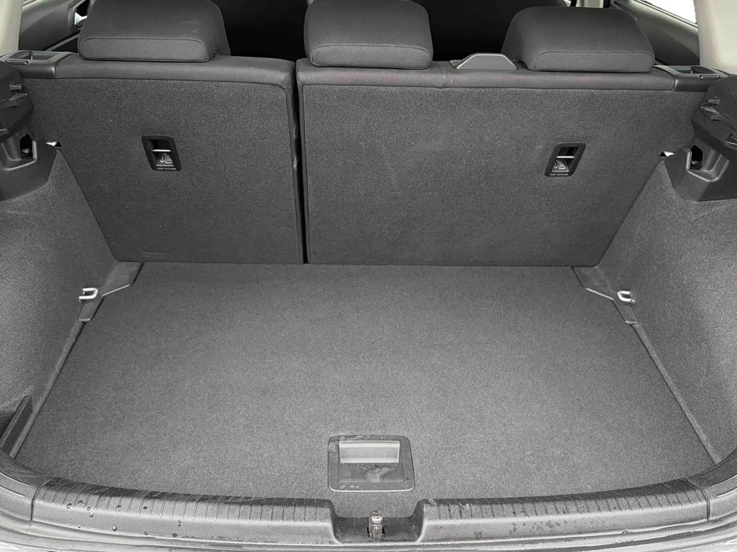 Coffre ouvert vu de l'arrière d'une Volkswagen Polo grise, montrant l'espace de chargement et les dossiers de sièges arrière.