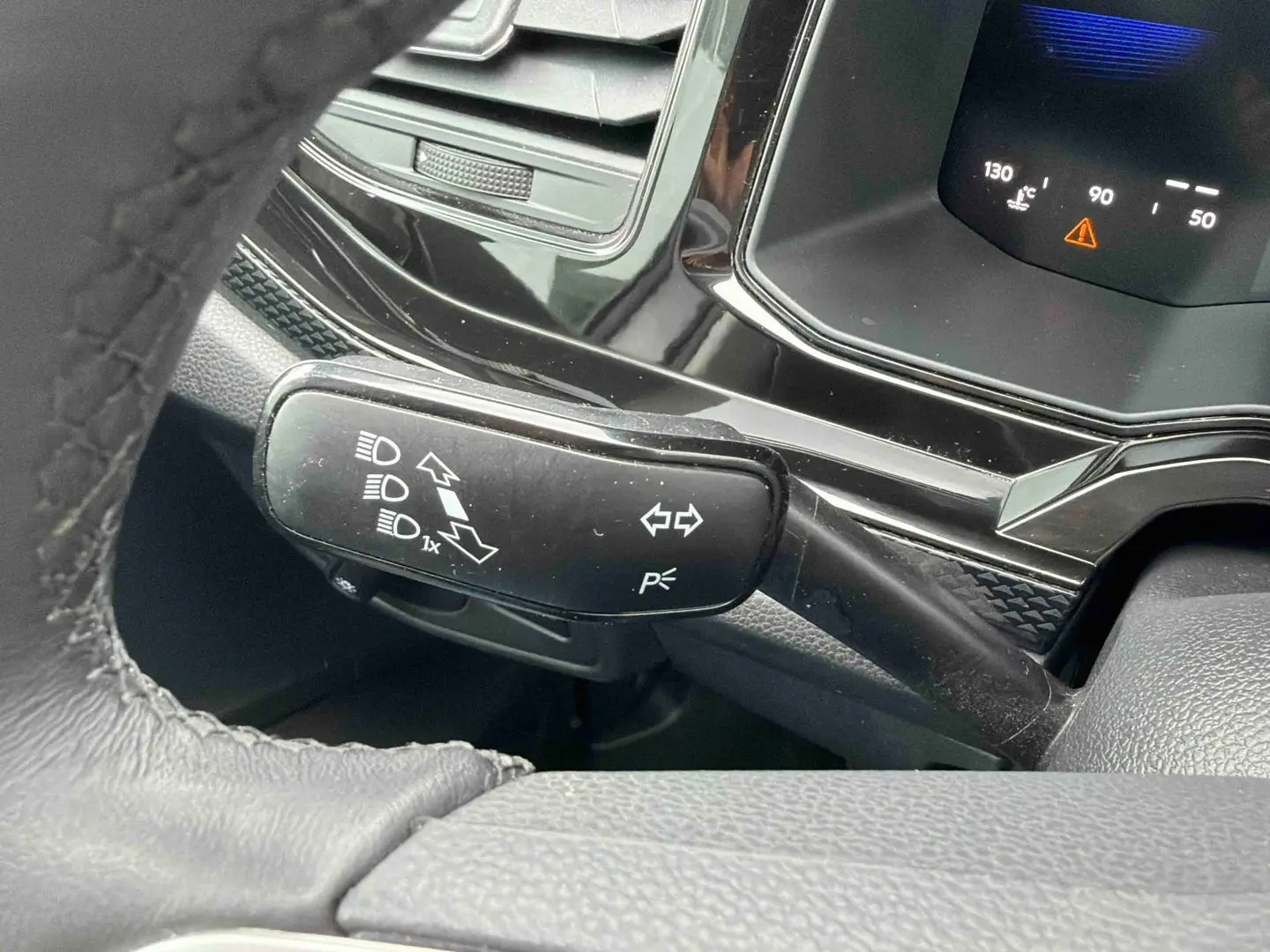 Gros plan sur la manette de clignotants noire et le combiné d'instruments digital dans l'habitacle d'une Volkswagen Polo grise.