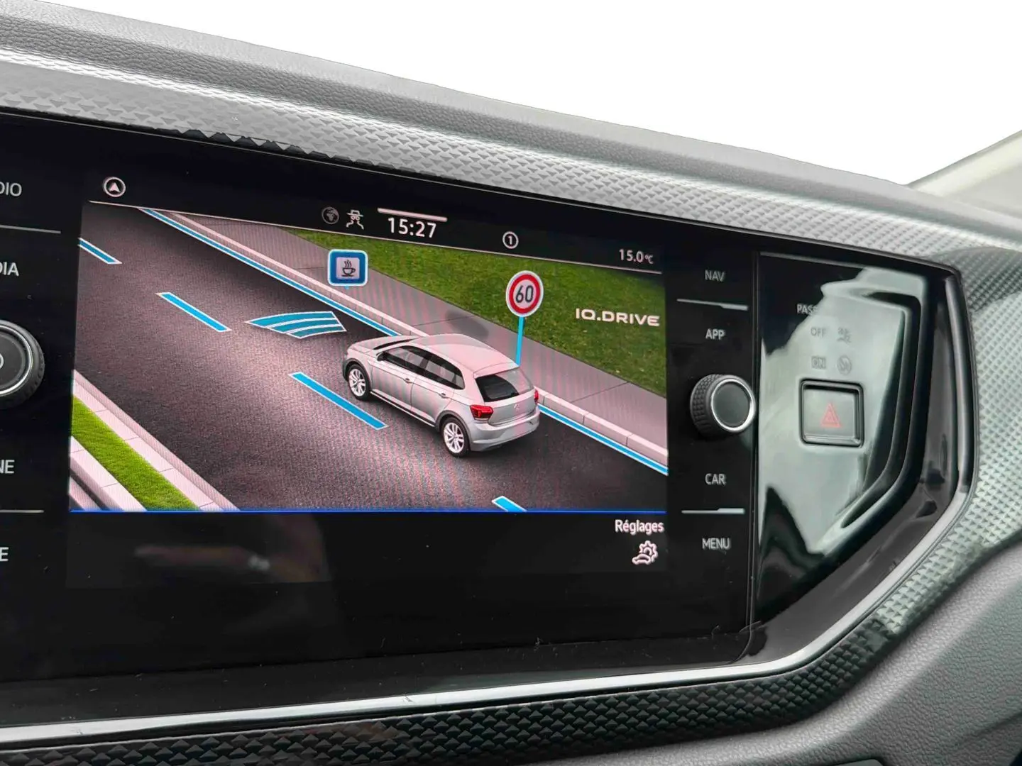 Écran tactile intérieur montrant l’interface de conduite assistée avec une Polo grise vue de trois quarts arrière.
