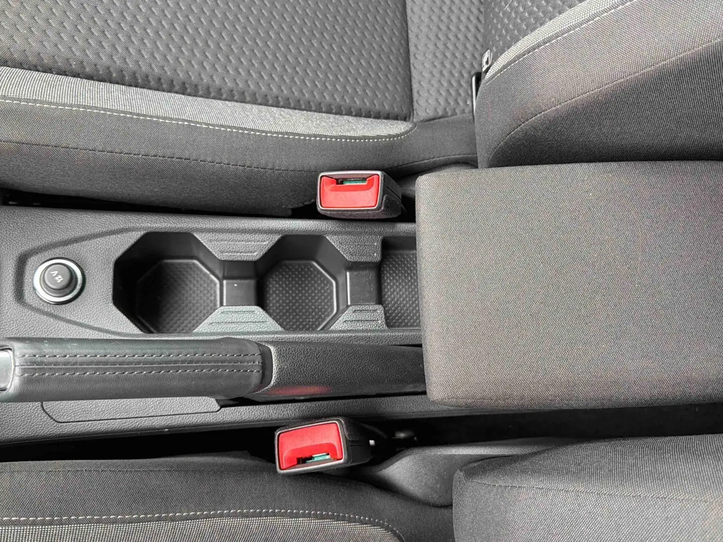 Vue rapprochée de la console centrale grise de la Volkswagen Polo 2025 avec accoudoir et porte-gobelets.