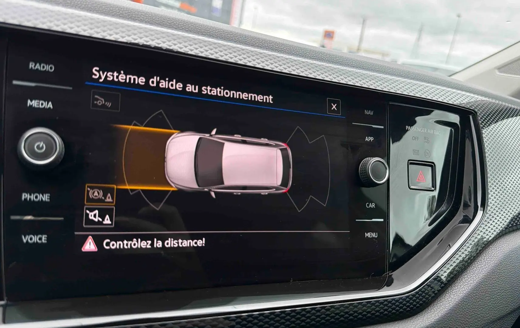 Écran tactile intérieur montrant l’aide au stationnement avec vue arrière de la Volkswagen Polo grise 2025.