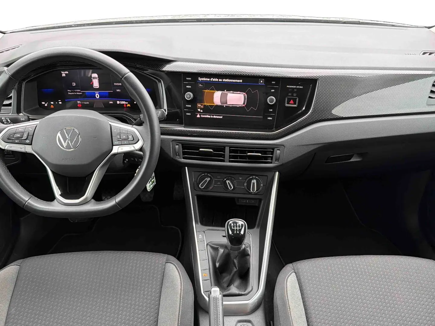 Vue intérieure frontale de la Volkswagen Polo grise 2025, avec tableau de bord digital et levier de vitesse manuel.