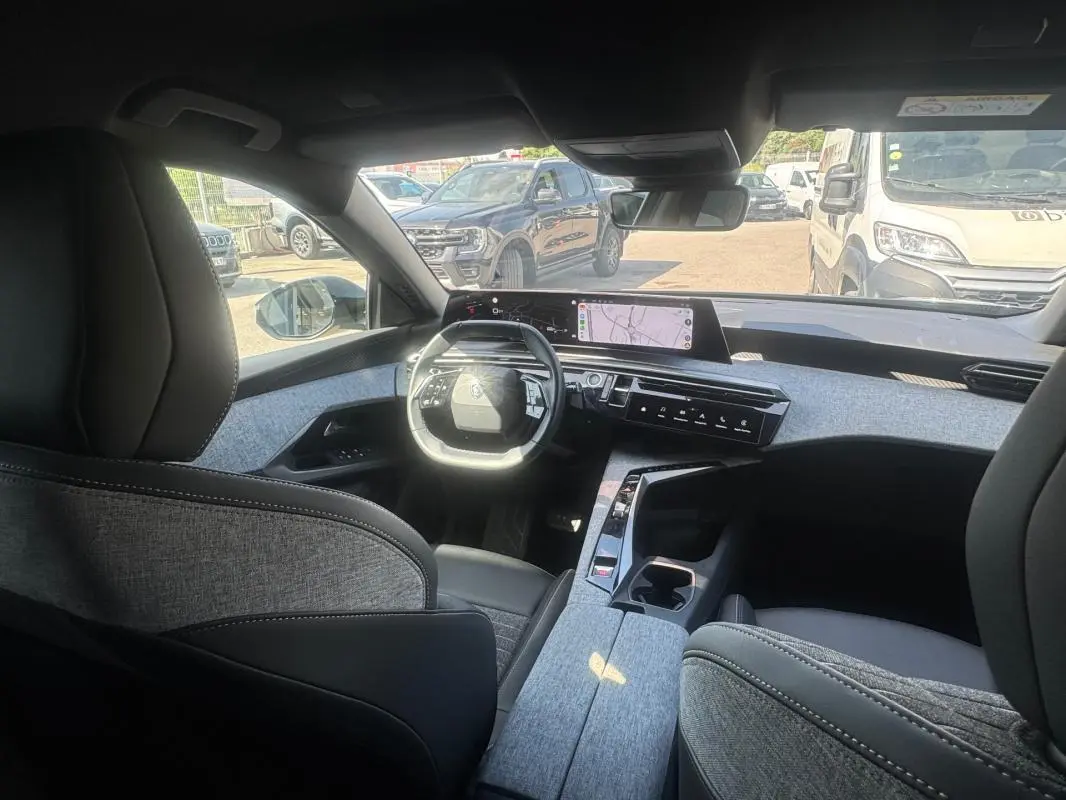 Vue intérieure avant du Peugeot 3008 Hybrid 136 e-DCS6 Allure 2025, avec cockpit numérique et sellerie grise.