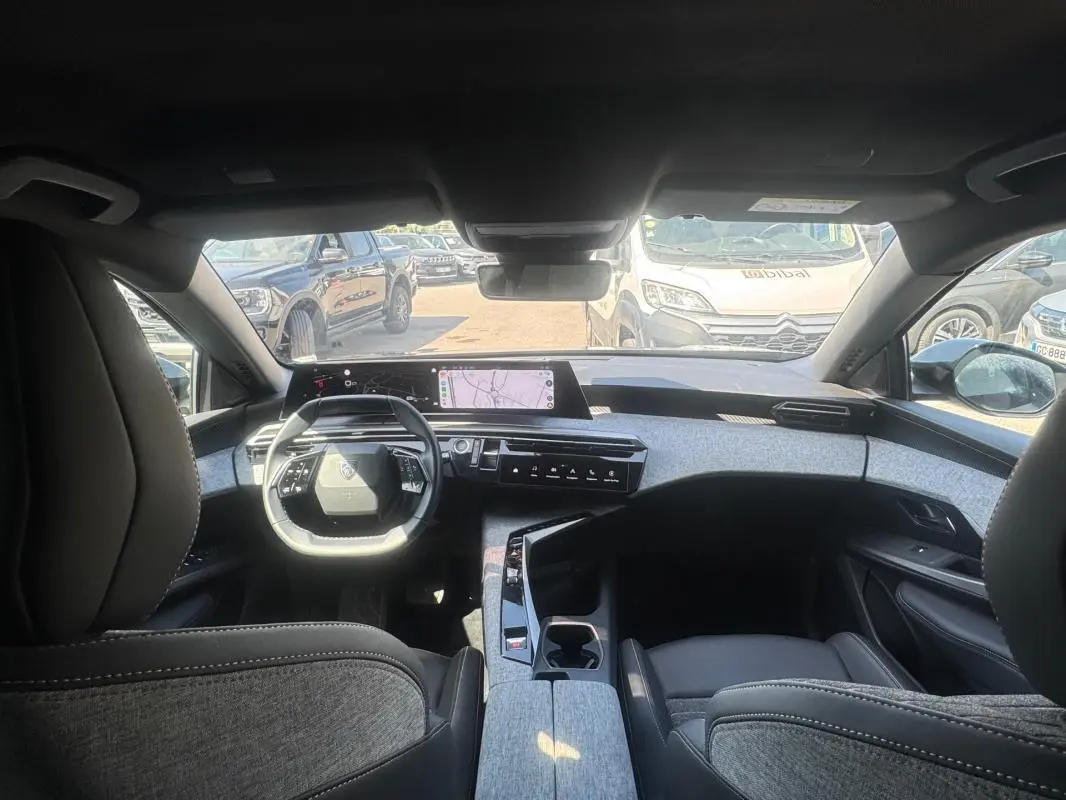 Vue intérieure avant du Peugeot 3008 Hybrid 136 e-DCS6 Allure 2025, mettant en valeur le cockpit numérique et les finitions grises.