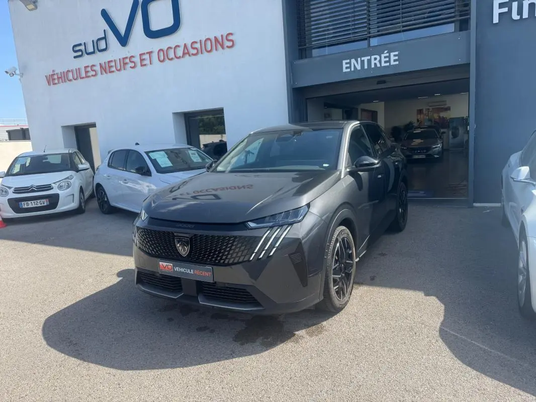 Peugeot 3008 Hybrid gris foncé en 3/4 avant droit, jantes alliage 19 pouces, devant entrée d’un showroom.