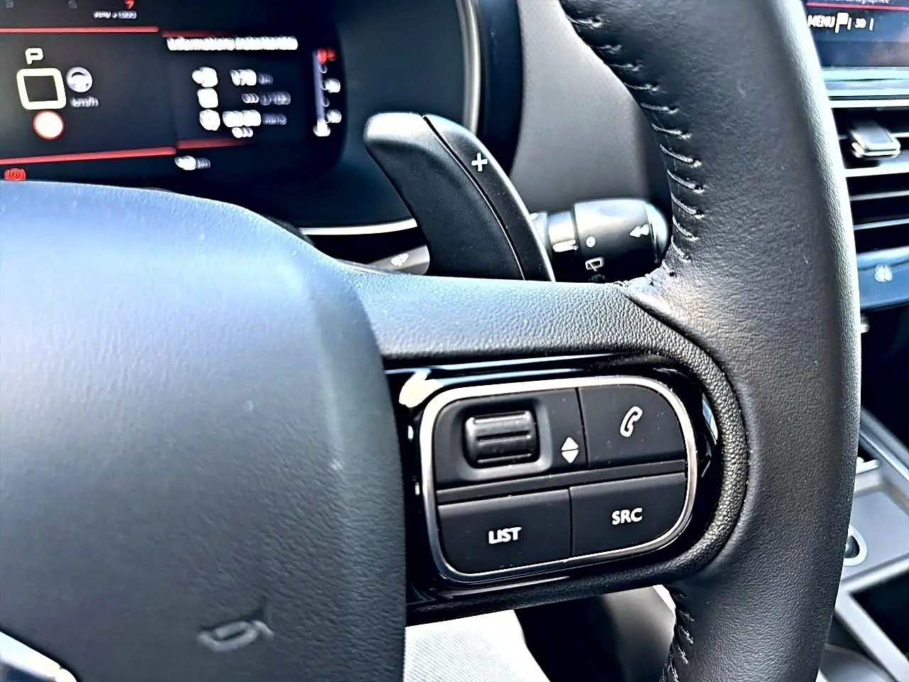 Gros plan sur le volant cuir noir côté gauche du Citroën C5 Aircross 2025 avec commandes multifonctions et palettes de boîte auto.