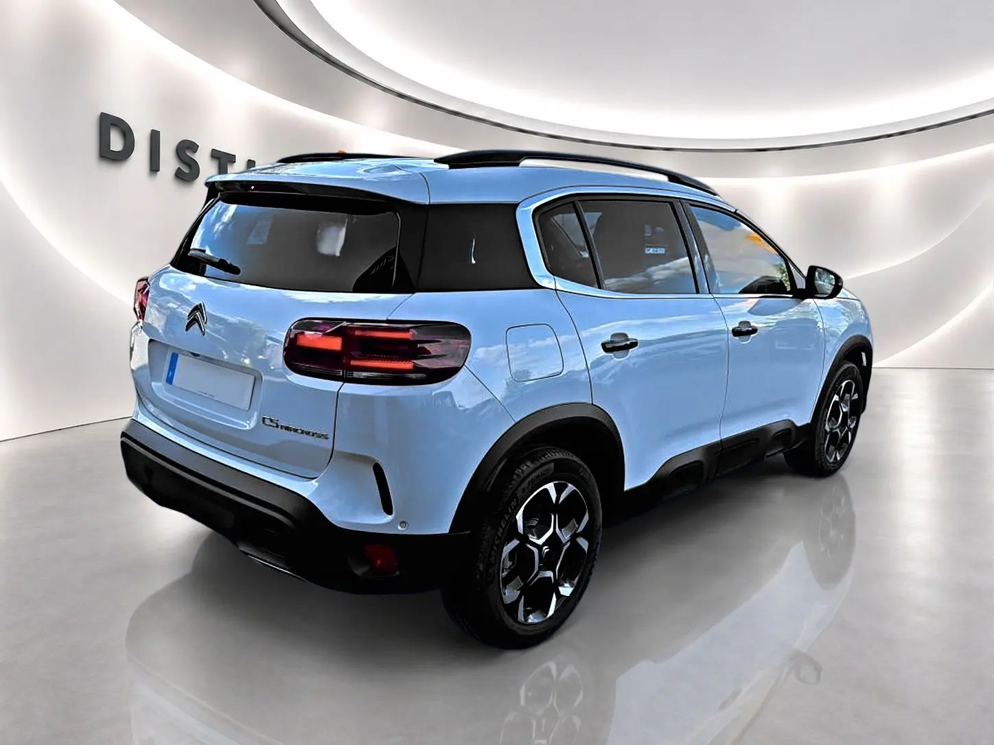 Vue 3/4 arrière droite d'un Citroën C5 Aircross bleu clair avec toit noir et jantes alu distinctives.